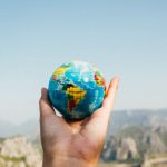 Traveling - Person Holding World Globe Facing Mountain